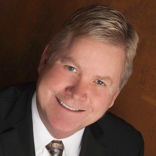 A man in suit and tie smiling for the camera.